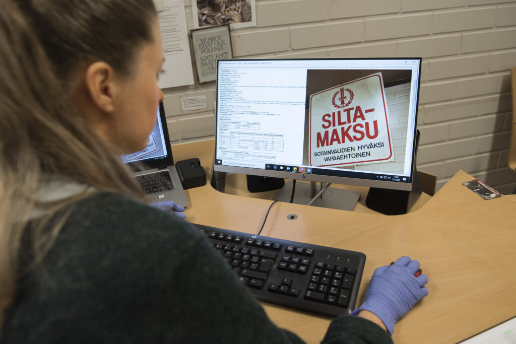 Kuvassa museon työntekijä käsittelee kokoelma-aineiston tietoja tietokoneella.