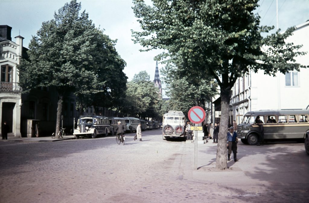 Katunäkymä, jossa vanhoja linja-autoja ja kevyttä liikennettä.